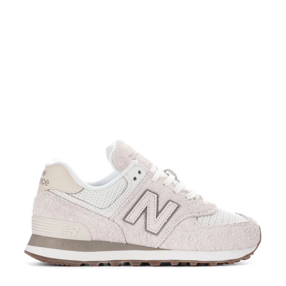 A pair of New Balance 574 women's sneakers in beige color with mesh, leather, and suede upper materials.