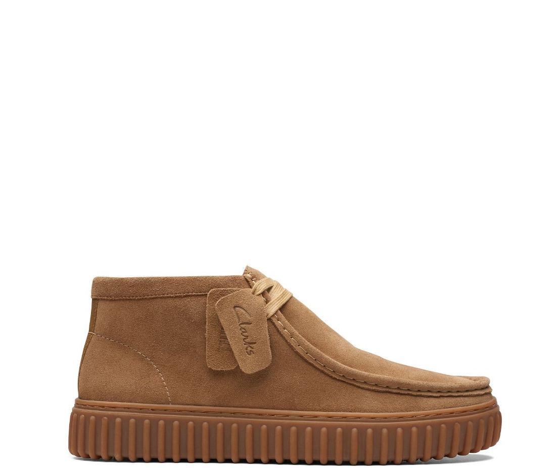 A brown suede ankle boot with a lace-up design and a bold, ribbed outsole.