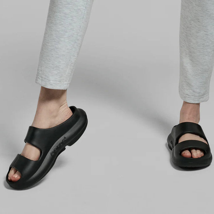 Person wearing black sandals on a plain background