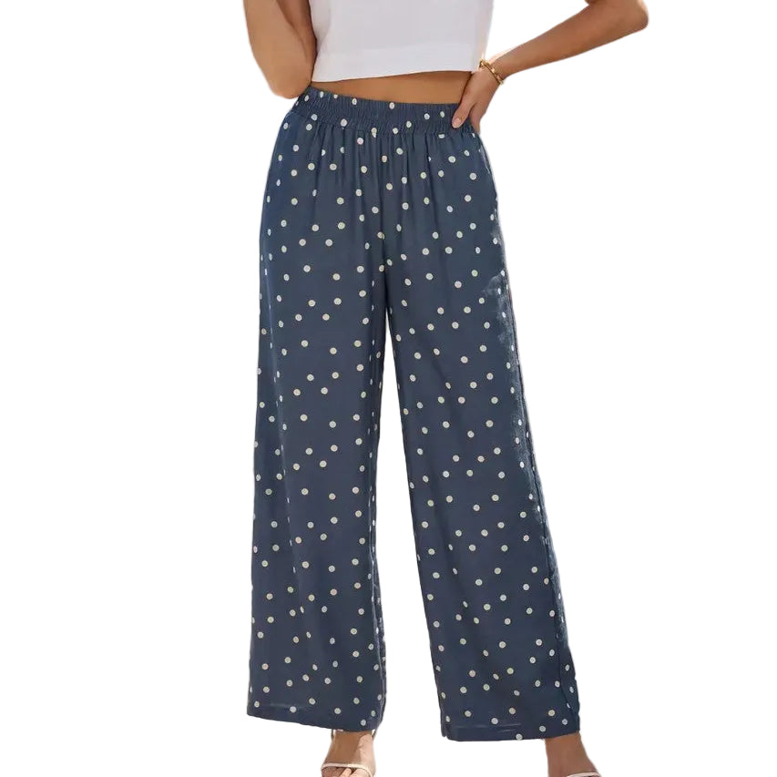 Woman wearing a white top and navy pants with star pattern on a sunlit patio with ocean view.