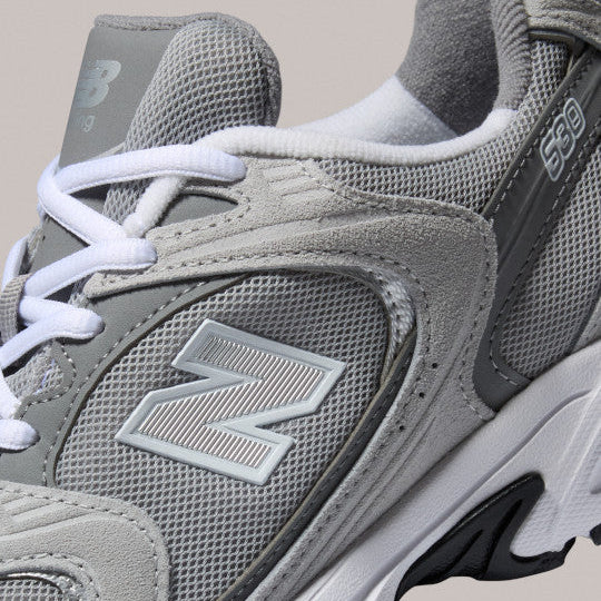 Gray New Balance sneaker with white laces on a beige background