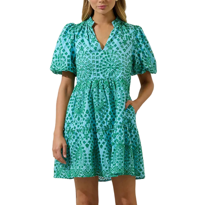 Woman wearing a green patterned dress against a plain background