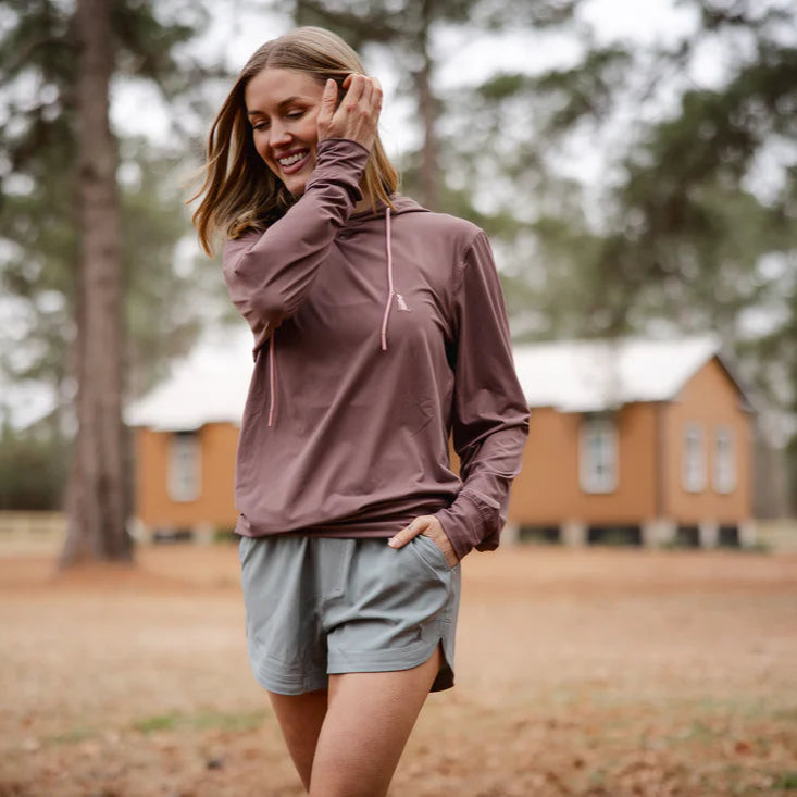 Woman in athletic wear standing in a park with wooden cabins in the background