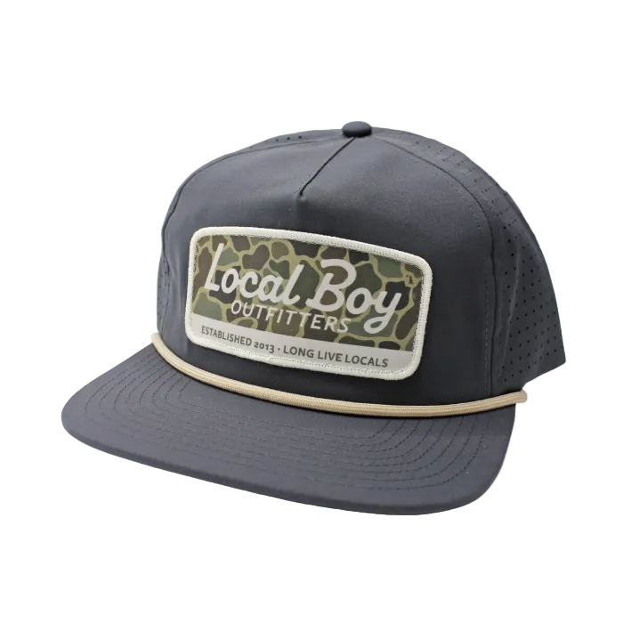 A dark gray snapback cap with a front patch reading 'Local Boy Outfitters' in white script over a green camouflage pattern, featuring a beige stripe around the brim. A yellow 'NEW' badge is in the top-left corner.