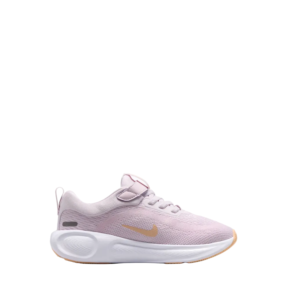 A Nike running shoe in light pink with a gold Swoosh logo, white midsole, and a hook-and-loop strap closure, shown from a side profile on a white background.