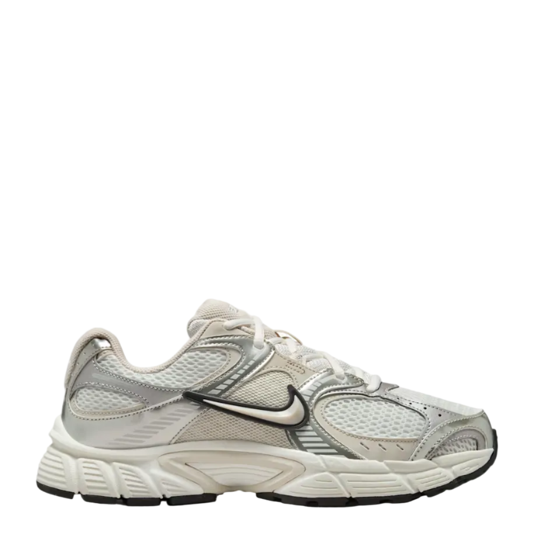 A Nike running shoe in a light beige and silver colorway, featuring a mesh upper, synthetic overlays, and a chunky white midsole, shown against a plain white background.