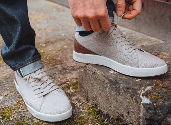 Person wearing light gray sneakers on a concrete surface