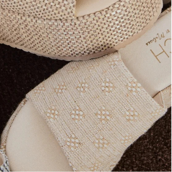 Close-up of beige high-heeled shoes with textured details on a white background